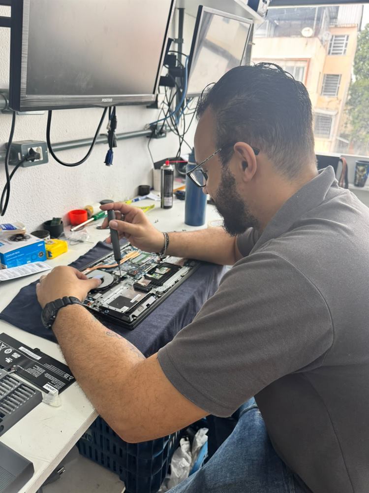 Técnico da RDO Informática abrindo um notebook corporativo na bancada para revisão e testes