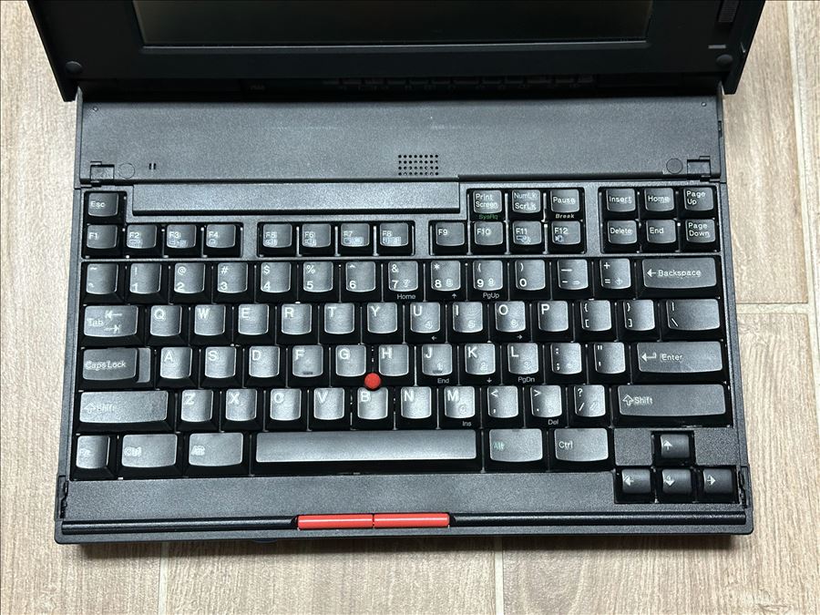 Teclado de ThinkPad antigo em close, com o TrackPoint vermelho no centro e os botões do mouse abaixo da barra de espaço